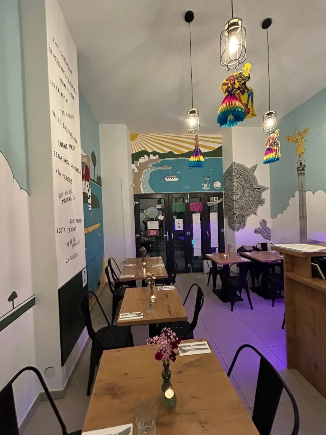 Wnętrze w stylu meksykańskim z kolorową aranżacją i muralami przedstawiającymi słynne zabytki Meksyku, m.in. Paseo de la Reforma i Xochimilco